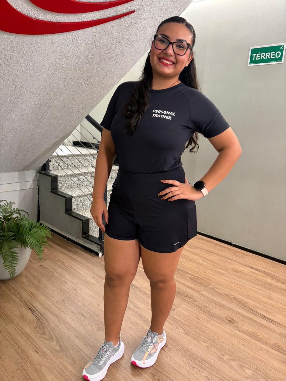 Flávia Layenne, personal trainer, sorrindo no ambiente de academia